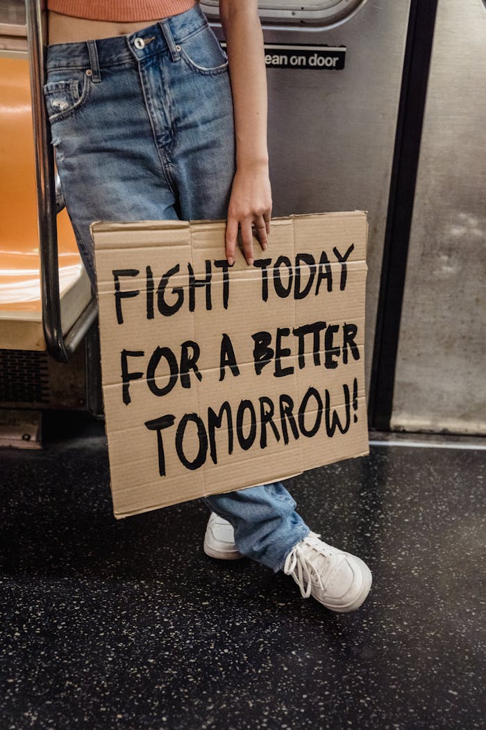 A person holding a protest sign in a subway advocating for a better future.